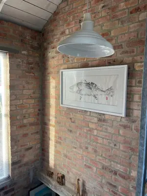 a brick wall with a picture and a light fixture at The Treehouse Suite in Hermanus
