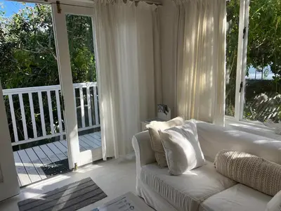 a living room with a white couch and a large window at The Treehouse Suite in Hermanus