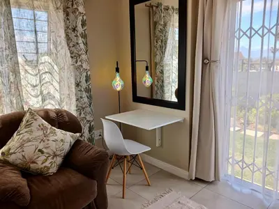 a living room with a table and a chair and a mirror at 22's Company in Cape Town