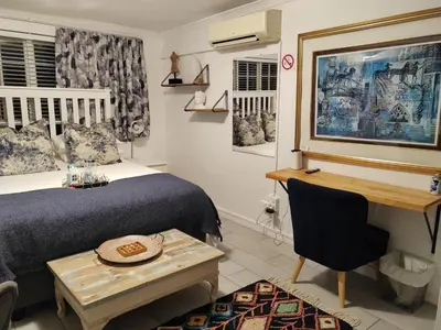 a bedroom with a bed and a desk and a table at La Damon 1 in Paarl