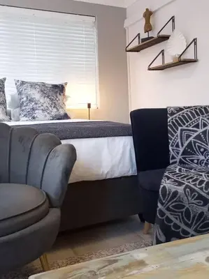 a bedroom with a bed and a couch and a chair at La Damon 1 in Paarl