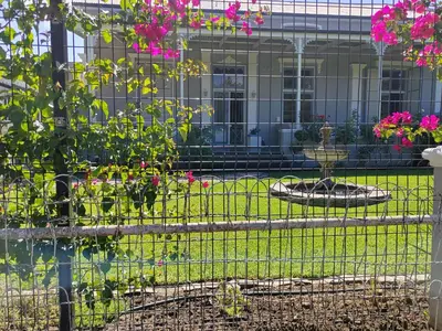 a fence in front of a garden with pink flowers at La Damon 2 in Paarl