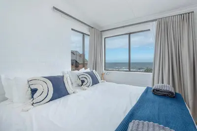 a bedroom with a bed with a view of the ocean at The Atlantic in Onrus in Hermanus