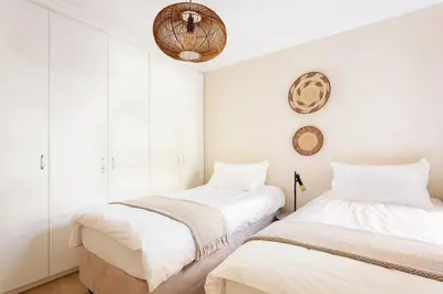 two beds in a room with white walls at Dolphin Beach cabana Luxe beach cabana voor 4 personen direct aan het strand in Table View