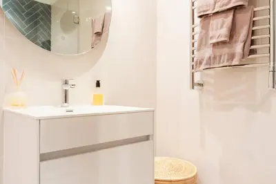 a white bathroom with a sink and a mirror at Dolphin Beach cabana Luxe beach cabana voor 4 personen direct aan het strand in Table View