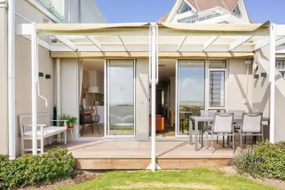 a patio with a table and chairs on a deck at Dolphin Beach cabana Luxe beach cabana voor 4 personen direct aan het strand in Table View