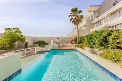 a swimming pool in front of a building at Dolphin Beach cabana Luxe beach cabana voor 4 personen direct aan het strand in Table View