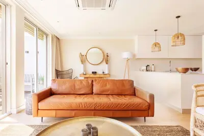 an orange leather couch in a living room with a kitchen at Dolphin Beach cabana Luxe beach cabana voor 4 personen direct aan het strand in Table View