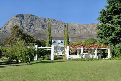 a white house with a mountain in the background at Farm Lorraine Lake Cottage, Loft Cottage and Garden Cottage in Franschhoek