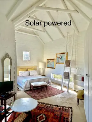 a bedroom with a bed and a desk and a tv at The Annex in Pringle Bay