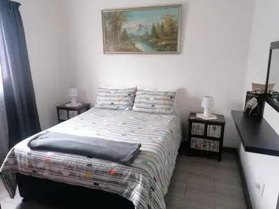 a bedroom with a bed and a painting on the wall at Kosies Nest Gastehuis in Cape Town