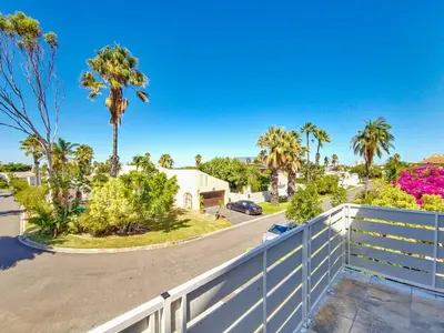 a house with a white fence and palm trees at Tranquil Family Escape: Pool Balcony in Cape Town