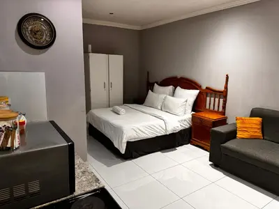 a bedroom with a bed and a couch and a tv at Mila Lodge 1 in Cape Town