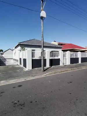 a white house with a white fence and a street at Mila Lodge 1 in Cape Town