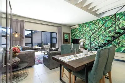 a living room with a wooden table and green wallpaper at Meerendahl Luxury Apartments at Heritage Square in Durbanville