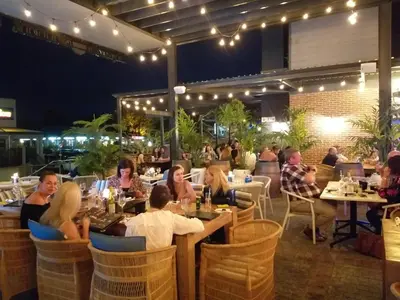 a group of people sitting at a restaurant at night at Meerendahl Luxury Apartments at Heritage Square in Durbanville