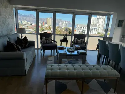 a living room with a couch and chairs and a large window at St Clouds Strand in Strand