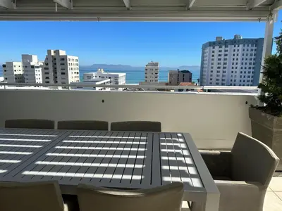 a table and chairs on a balcony with a view of a city at St Clouds Strand in Strand