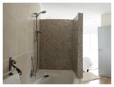 a bath tub in a bathroom with a shower at St Clouds Strand in Strand
