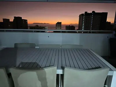 a table and chairs on a balcony with a sunset at St Clouds Strand in Strand