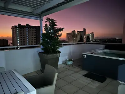 a rooftop terrace with a tree and a bath tub at St Clouds Strand in Strand