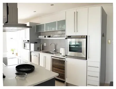 a kitchen with white cabinets and a counter top at St Clouds Strand in Strand