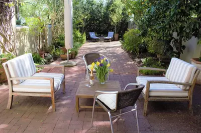 a patio with three chairs and a table with flowers on it at Le Habitat 6 in Franschhoek