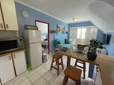 a kitchen with a table and a refrigerator at De Blauwvoet - Flamingo Apartment in Cape Town