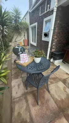 a patio with a table and chairs with a plant at De Blauwvoet - Flamingo Apartment in Cape Town