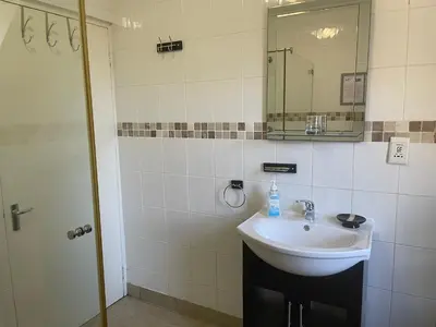 a bathroom with a sink and a mirror at De Blauwvoet - Meerkat (Sunset Beach) in Cape Town