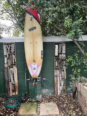 a surfboard sitting on top of a green wall at De Blauwvoet - Meerkat (Sunset Beach) in Cape Town