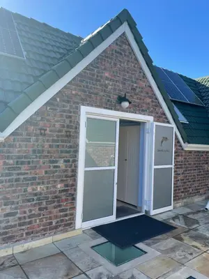 a door to a brick house with solar panels at De Blauwvoet - Dolfyn (Sunset Beach) in Cape Town