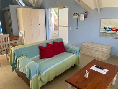 a living room with a couch and a table at De Blauwvoet - Dolfyn (Sunset Beach) in Cape Town