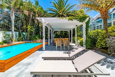 a swimming pool with a white pergola next to a house at The Atrium in Somerset West