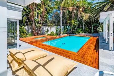 a swimming pool with a deck and chairs and a house at The Atrium in Somerset West