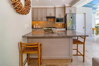 a kitchen with a counter with chairs and a refrigerator at The Atrium in Somerset West