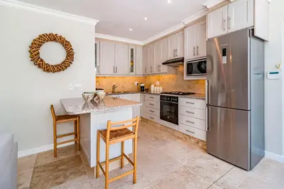 a kitchen with white cabinets and a stainless steel refrigerator at The Atrium in Somerset West