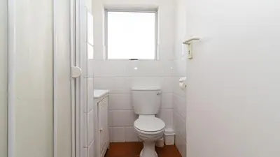 a white bathroom with a toilet and a window at 241 hermanus beach club in Hermanus