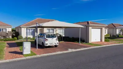 a white car parked under an umbrella in front of a house at 241 hermanus beach club in Hermanus