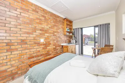 a brick wall in a bedroom with a bed at Blouberg Studio Apartments in Bloubergstrand