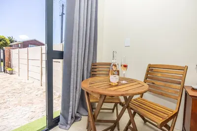 a table with a bottle of wine and two chairs at Blouberg Studio Apartments in Bloubergstrand
