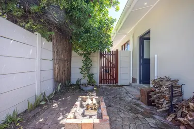 a house with a tree next to a fence at Blouberg Studio Apartments in Bloubergstrand