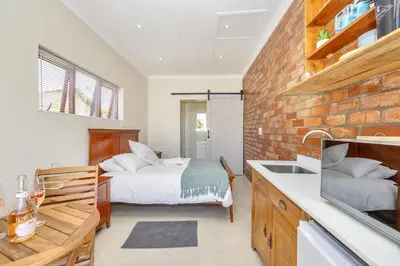 a bedroom with a bed and a kitchen with a sink at Blouberg Studio Apartments in Bloubergstrand