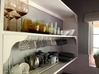 a kitchen shelf with dishes and glasses on it at Comfy Greyton Cottage for Four in Greyton