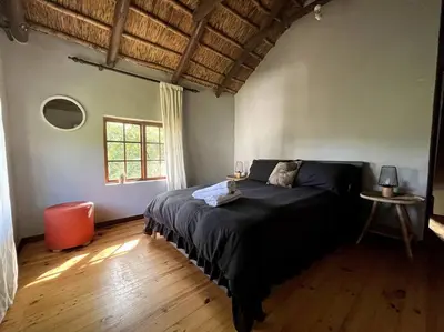 a bedroom with a large bed in a room with wooden floors at Comfy Greyton Cottage for Four in Greyton
