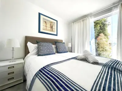 a bedroom with a bed and a large window at Coastal House - 2BR and Self catering in Cape Town