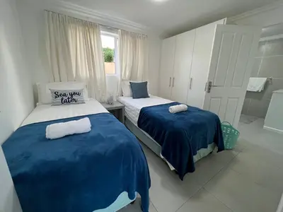 a bedroom with two beds with blue and white sheets at Coastal House - 2BR and Self catering in Cape Town