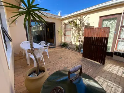 a patio with a table and a potted plant at Blouberg Cosy 2 bedroom house in Cape Town