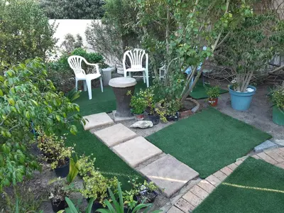 a garden with two chairs and a table and grass at Blouberg Cosy 2 bedroom house in Cape Town