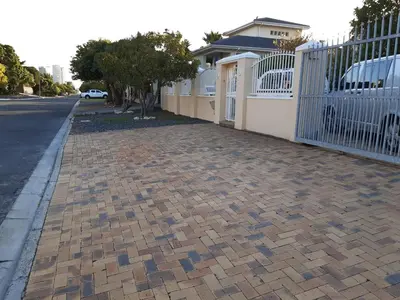 a brick sidewalk next to a white fence at Blouberg Cosy 2 bedroom house in Cape Town